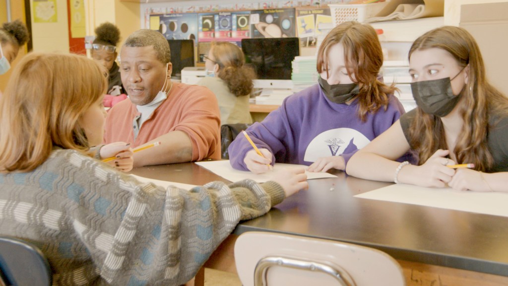 Black and white adults and children drawing in a classroom
