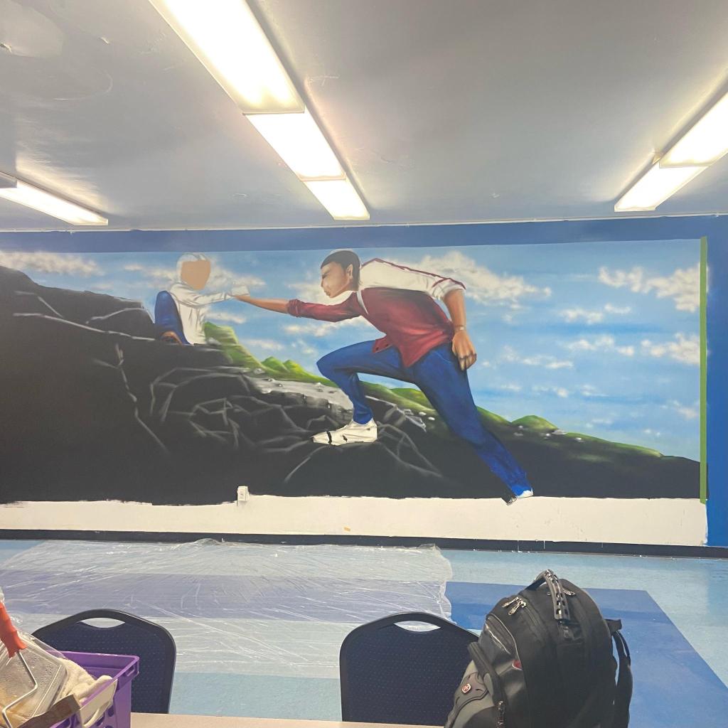 A mural of a black teenager climbing a mountain and giving a high five to someone nin a white suit